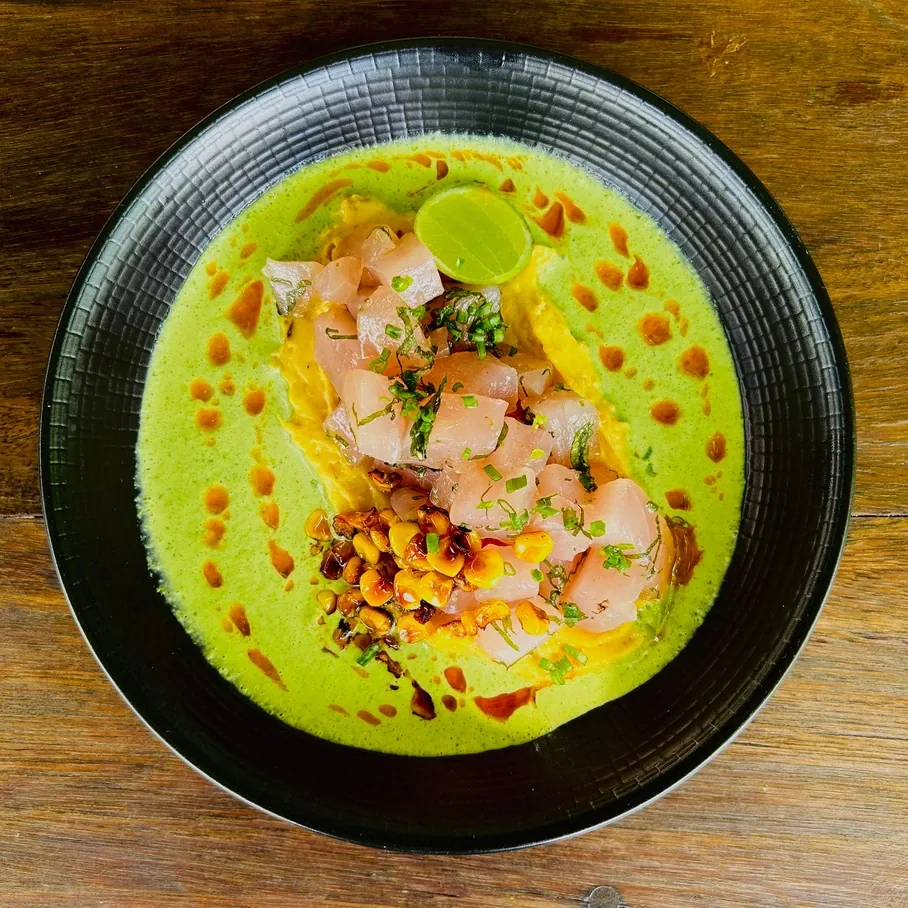 Fish crudo over a green herb broth with charred corn and lime, seen from above at Seed