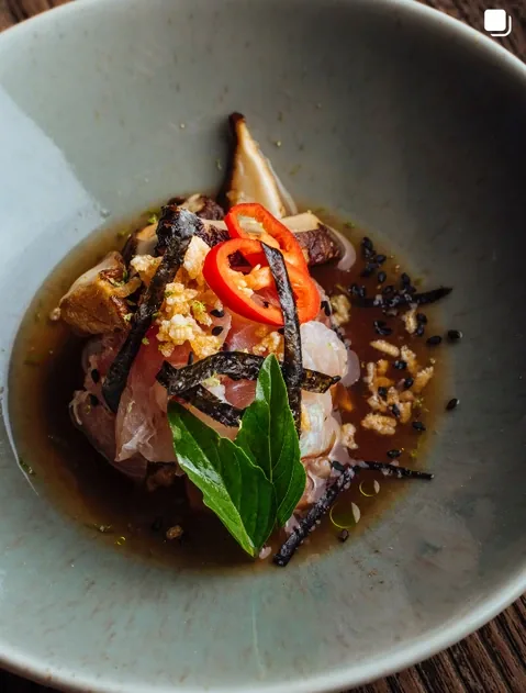 Sliced pork in broth with chilli, crisped rice, nori and fresh herbs, plated at Seed