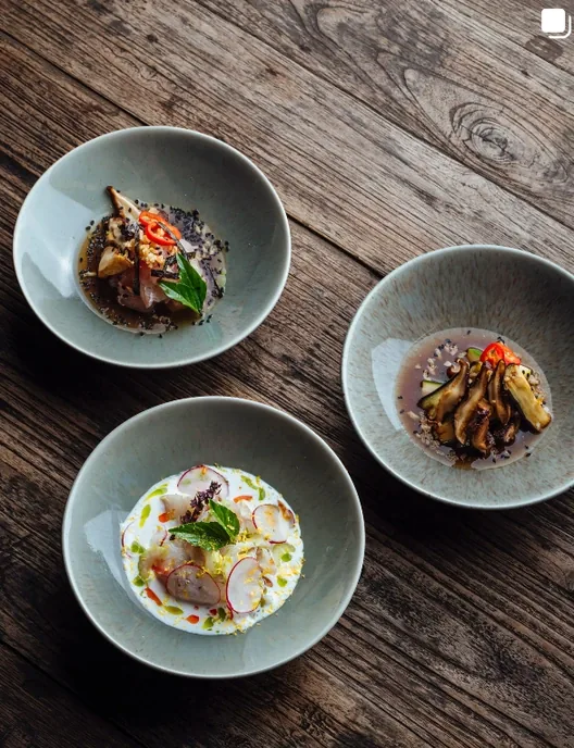 Three small plates from the Seed menu laid out on a weathered wooden table