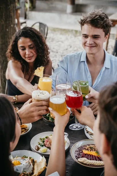Guests toasting with cocktails at an outdoor table at Seed in Bingin