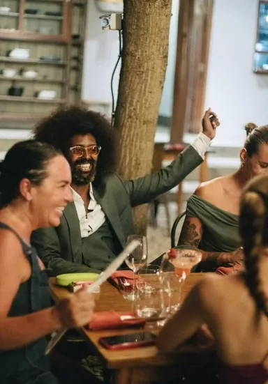 Guests laughing around a candlelit table at Seed, beside the tree that grows through the dining room