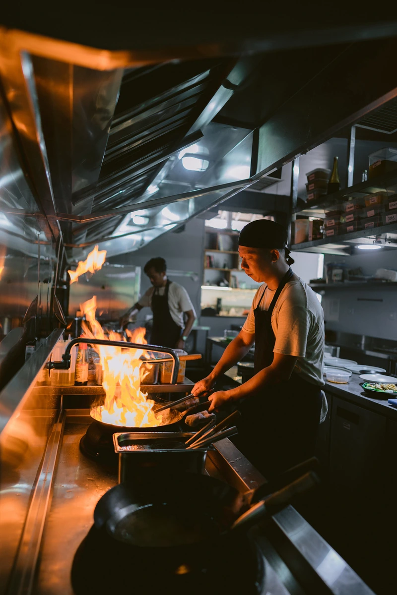 A cook tossing a wok over open flame in the Seed kitchen