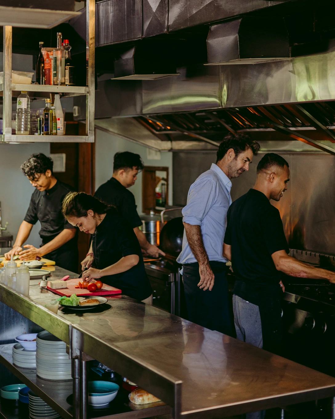 Five cooks working side by side along the Seed kitchen line, prepping under the extraction hood