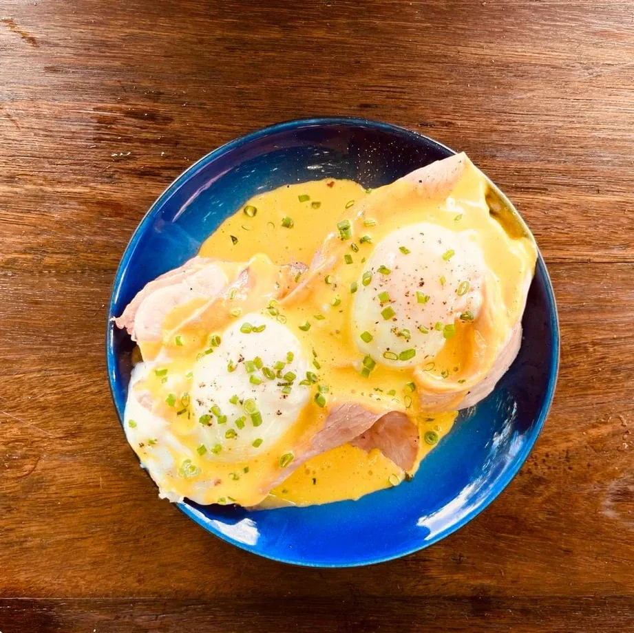 Eggs Benedict with hollandaise on a blue plate from the Seed breakfast menu